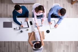 Top-down view of business professionals in a meeting discussing documents and using digital devices